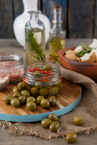 Close up of green olives by containers on cutting board at table
