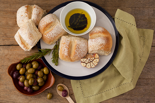 Overhead view of bread bread in plate by olives on table
