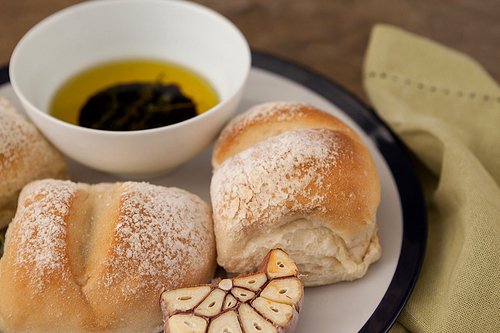 Close up of bread by olive oil in bowl on plate at table