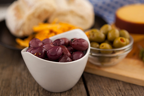 Olives in bowl by cutting board on table
