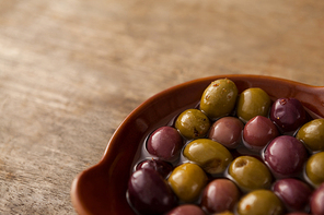 High angle view of olives with oil in container on wooden table