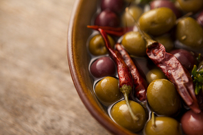 Close up of olives with red chili pepper and oil in bowl