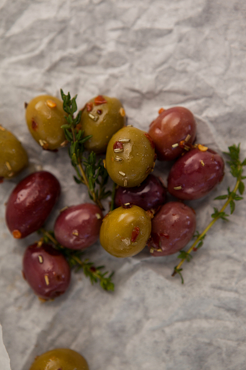 Close up of olives with thyme on wax paper