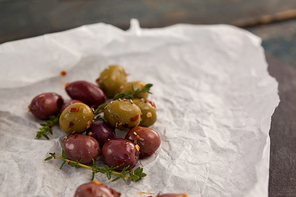 High angle view of olives with thyme on wax paper