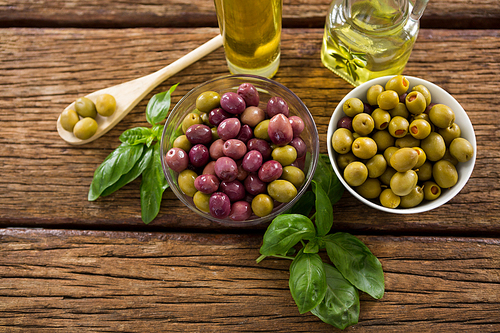 Marinated olives with ingredients on wooden table