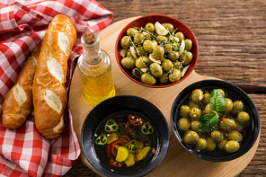 Close-up of marinated olives, bread and olive oil on heart shape board