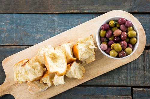 Marinated olives with bread pieces on chopping board