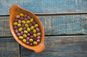 Pickled olives in bowl on wooden table