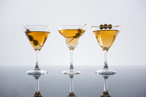 Close-up of cocktail with olives on table against white background