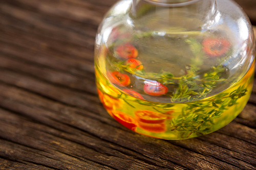 Close-up of olive oil with rosemary and red chili pepper on table