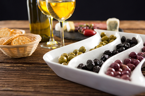 Close-up of marinated olives with bottle of wine and food on table