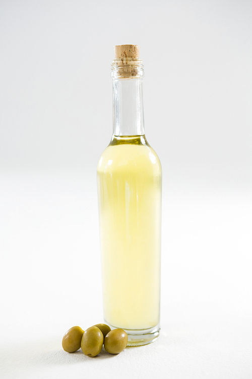 Green olive oil in bottle against white background