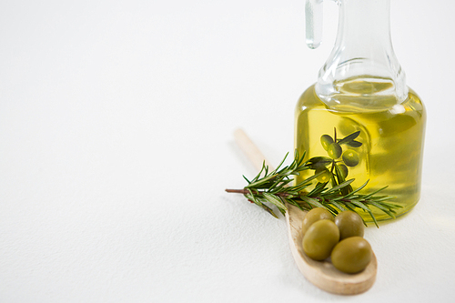 Marinated olives with oil bottle and herb against white background