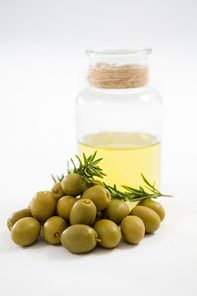 Marinated olives with oil bottle and herb against white background