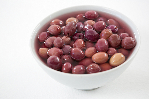 Close-up marinated olives in bowl against white background