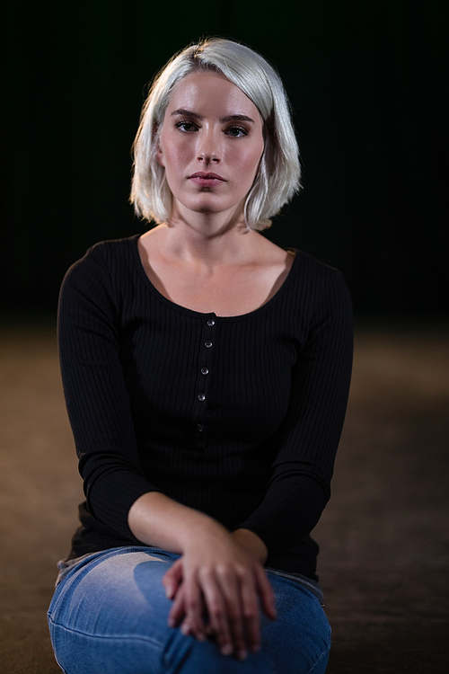 Confident woman sitting against black background