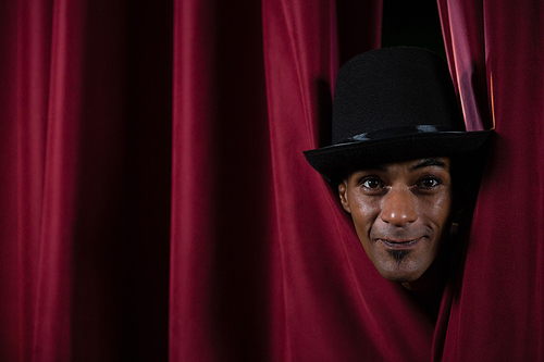 portrait of dance dancer peeking through a stage curtain