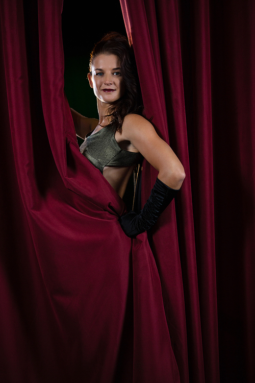 Portrait of female artist posing in front of massive red stage curtain