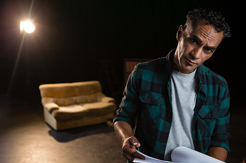 Portrait of actor holding his scripts on stage in theatre