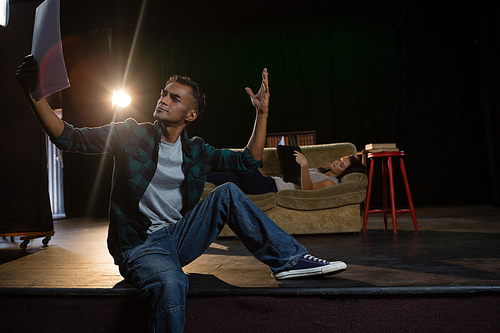 Actors reading their scripts on stage in theatre