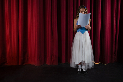 Female artist reading her scripts on stage in theatre