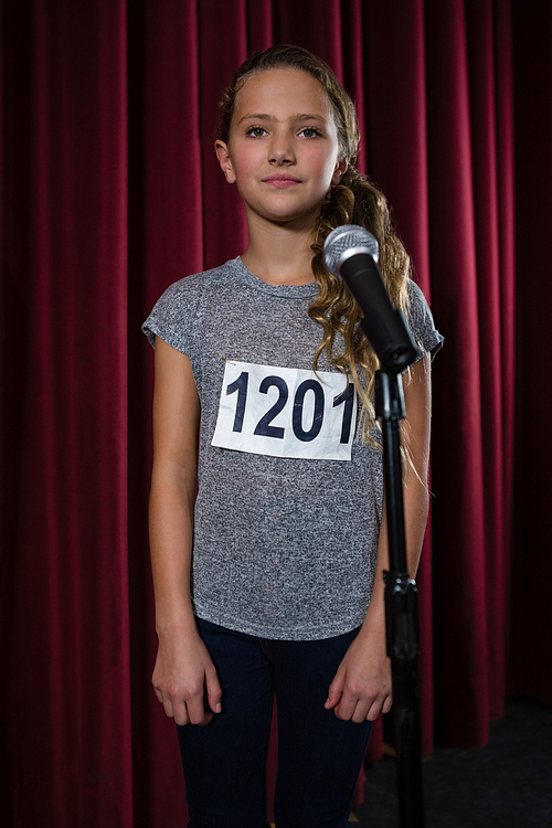 Girl standing front of microphone on stage in theatre