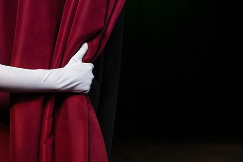 Close-up of hand in a white glove pulling curtain away