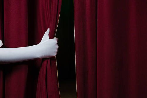 Close-up of hand in a white glove pulling curtain away