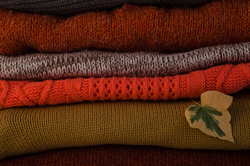 Close-up of woolen stack with autumn leaves