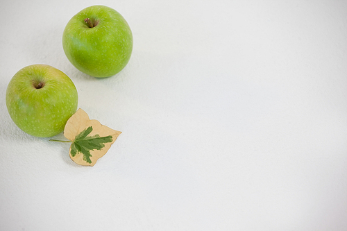 Green apples and autumn leaves on white background