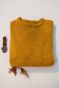 Overhead of warm clothing with watch on white background