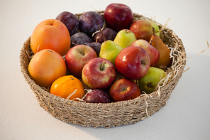 Close-up of various fruits in wicker basket against white background