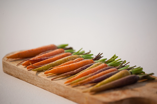 Close-up of carrots arranged on chopping board on white background