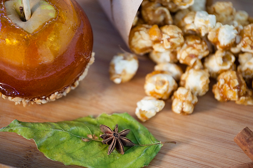 Close-up of popcorn, apple and apise on wooden table