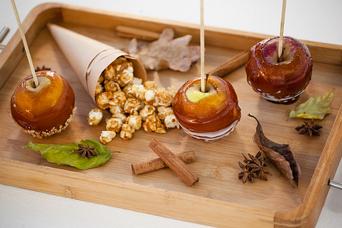 Close-up of popcorn, apple and apise on wooden tray