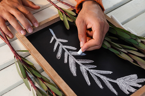 Close of hand drawing leaves on slate