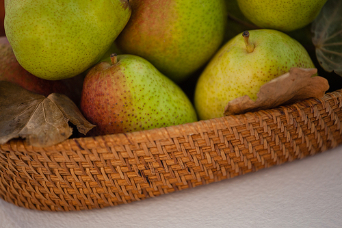 Close-up of pears in wicker basket against white background