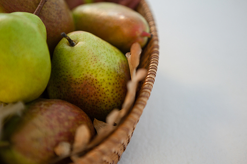 Close-up of pears in wicker basket on white background