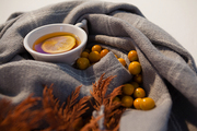 Close-up of autumn berry, lemon tea and leaves on blanket against white background
