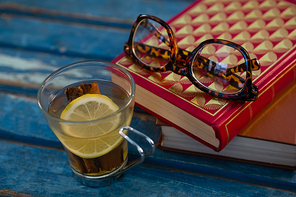 Close up of lemon tea by books and eyeglasses on wooden table