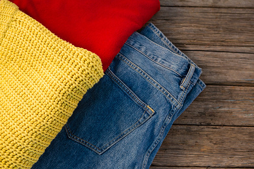 Overhead view of warm clothing with jeans on wooden table