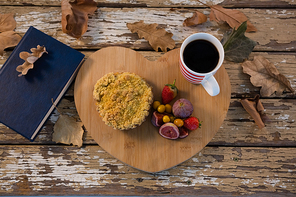 Overhead view of food with coffee cup on wooden tray by book at table