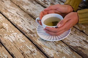 Cropped hand of woman holding tea at wooden table