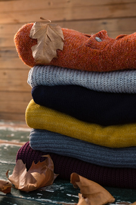 Stack of sweater on wooden table by wall