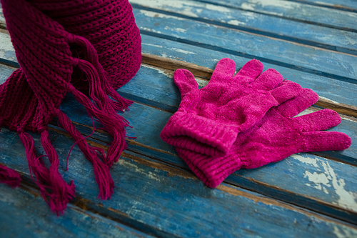 High angle view of pink muffler with gloves on wooden table