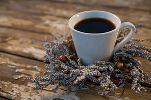 Close up of black coffee on dried plant at wooden table
