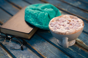 Close up of hot chocolate by cap and book on wooden table