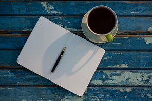 Overhead view of open book by tea cup on wooden table