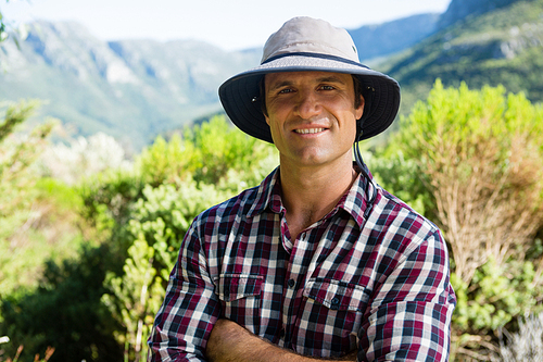 Portrait of smiling farmer standing with arms crossed in farm