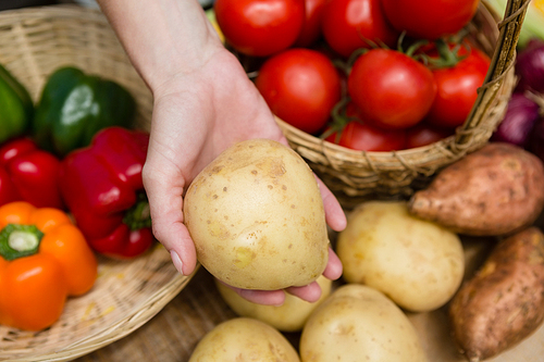 Close-up of woman holding fresh potato at vegetable stall